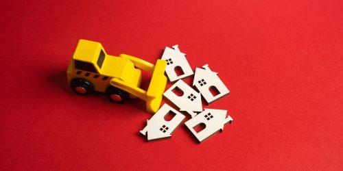 The bulldozer demolishes the figurines of the houses.